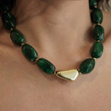 Gros plan sur le collier court MAISON DE L'AMOUR porté au cou, montrant les détails des perles vertes et le rendu sur la peau.