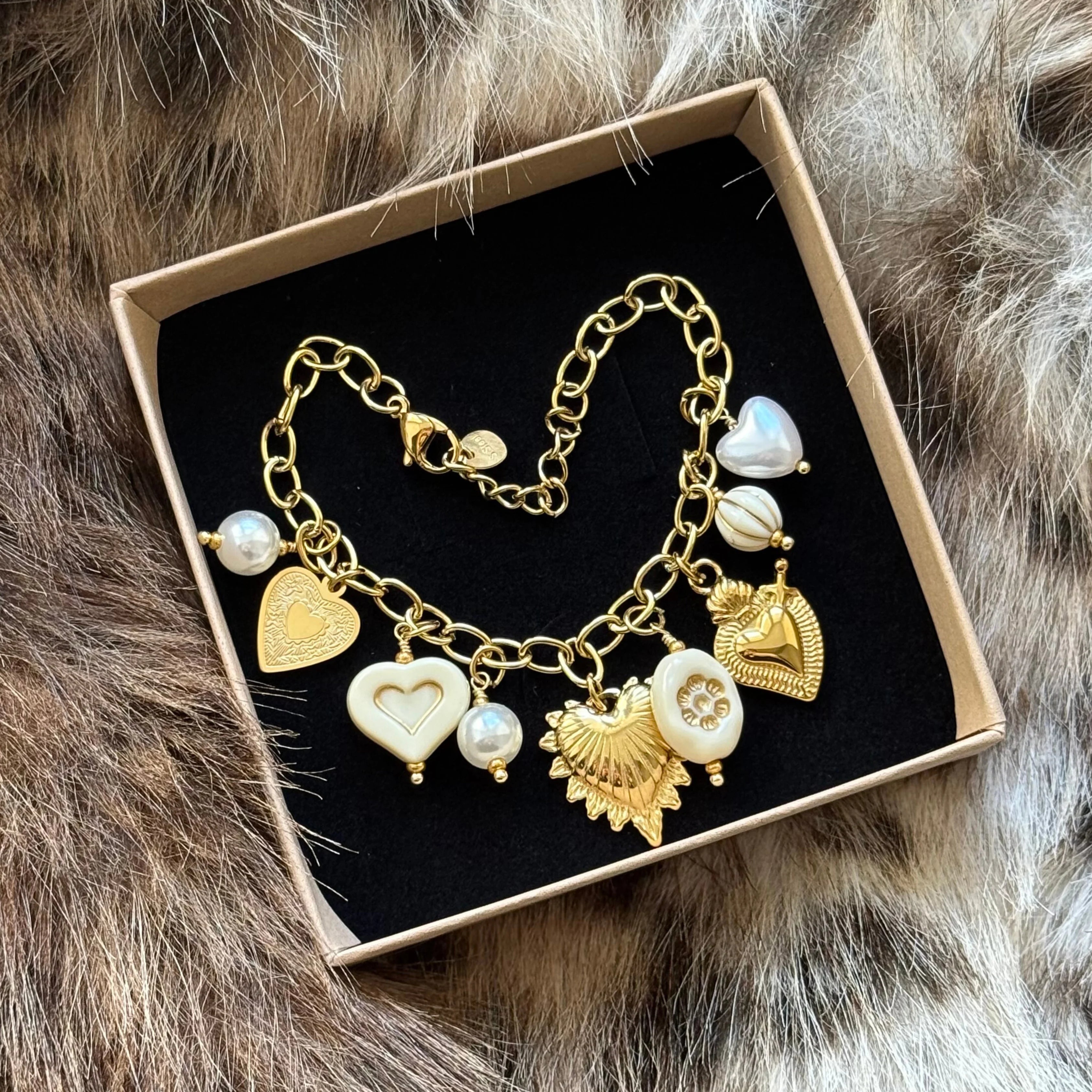 Bracelet à breloques présenté soigneusement dans une boîte cadeau noire et kraft, prêt à offrir.