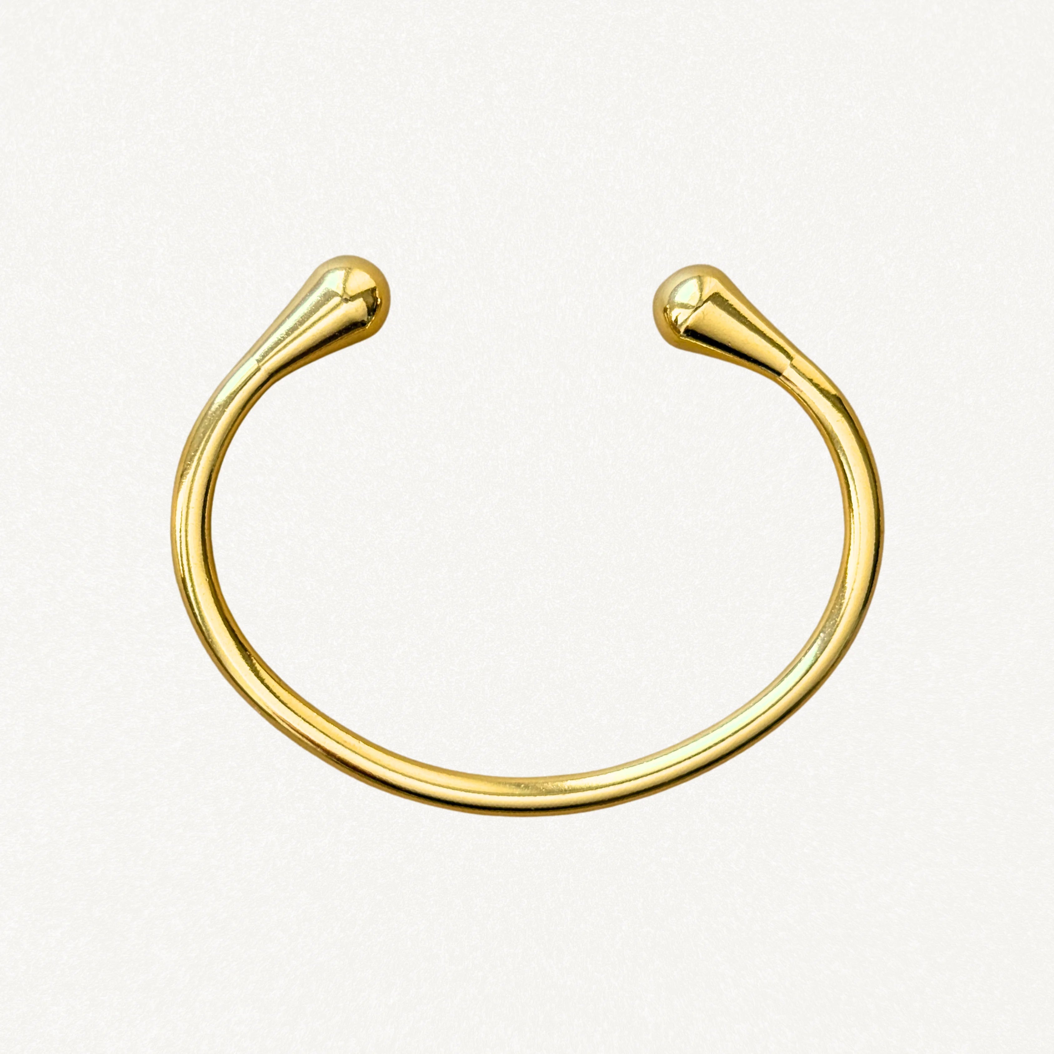 Vue de dessus d'un bracelet jonc ouvert doré montrant sa forme ovale ergonomique et ses finitions lisses.