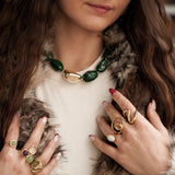 Idée de look chic : femme portant le collier à grosses perles vertes MAISON DE L'AMOUR associé à une accumulation de bagues dorées.