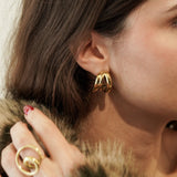 Créole triple rangs portée avec un manteau en fausse fourrure et une bague spirale assortie.