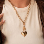 Femme portant le collier chaîne cœurs dorés MAISON DE L'AMOUR sur un t-shirt blanc, style rock chic avec veste en cuir.