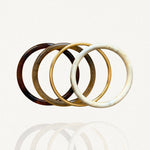 Ensemble de quatre bracelets joncs rigides : résine motif écaille de tortue foncée et claire, effet marbre blanc et métal doré simple sur fond blanc.