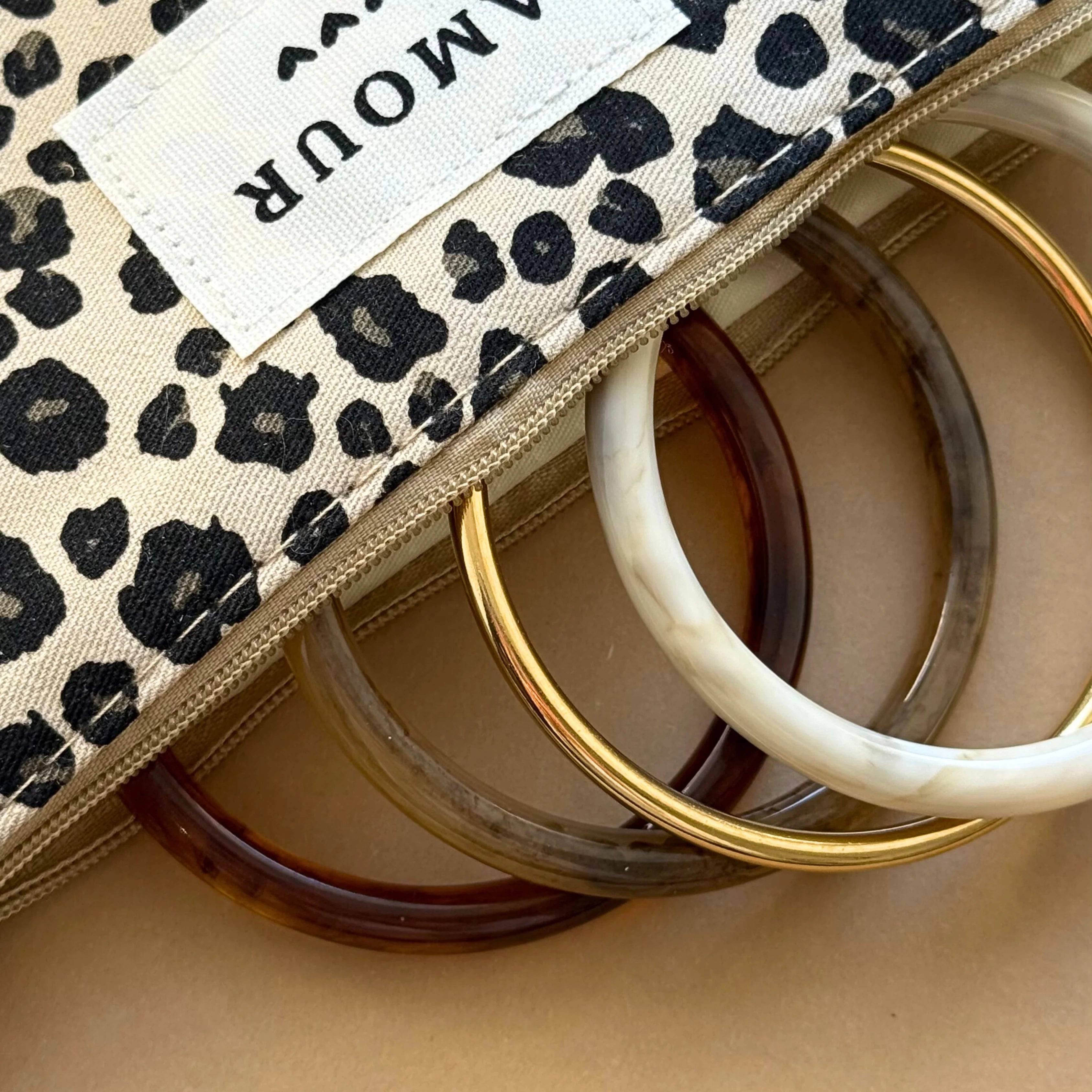Bracelets joncs glissés dans une trousse en toile motif léopard avec étiquette brodée Amour.