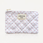 Pochette matelassée blanche à motifs petits cœurs rouges. Étiquette "AMOUR" et 3 cœurs noirs cousue au centre. Fermeture