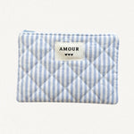 Pochette matelassée à rayures verticales bleues et blanches, avec étiquette "AMOUR" et 3 coeurs noirs. Fermeture éclair