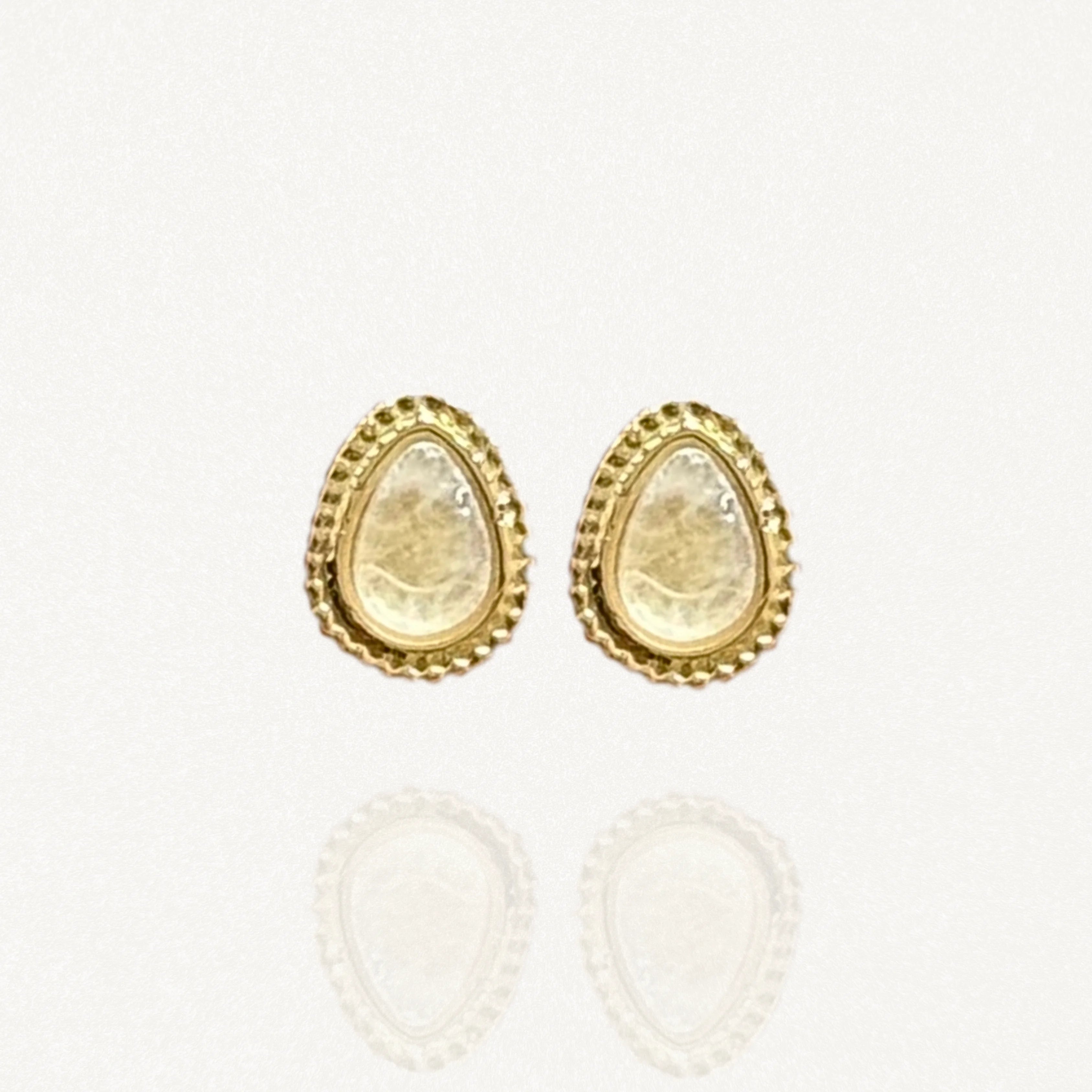 Paires de puces d'oreilles MAISON DE L'AMOUR forme goutte, pierre blanche nacrée effet pierre de lune sertie de doré sur fond blanc.