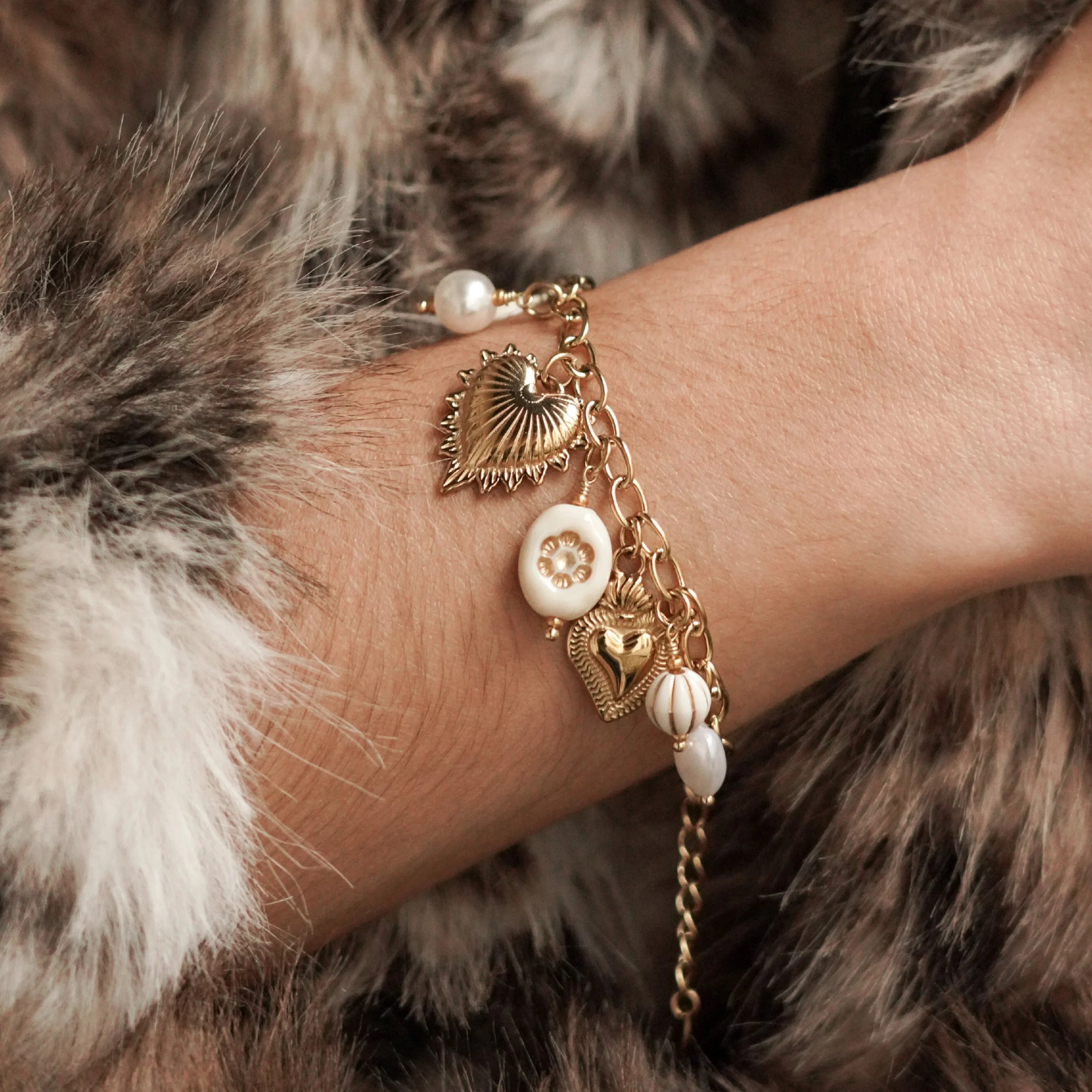 Bracelet chaîne à pendentifs cœurs et perles porté au poignet, accessoire de mode tendance pour femme.